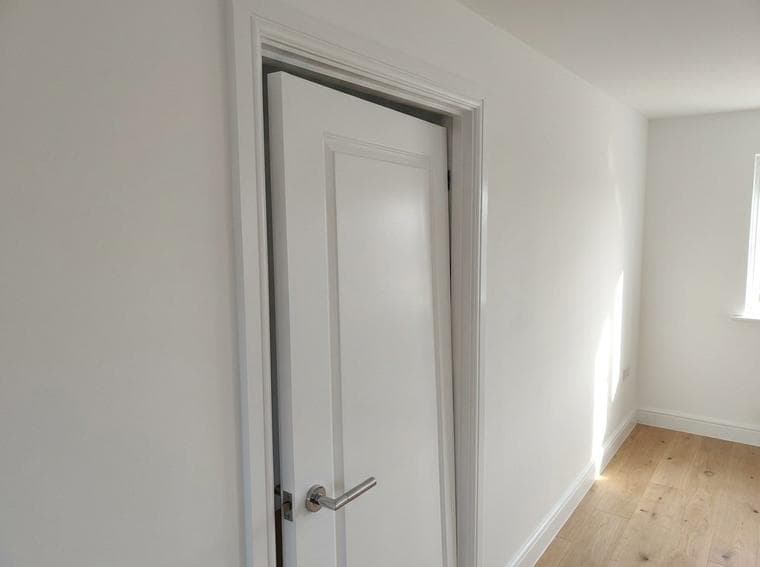 The bedroom door remained proud of the frame and did not latch when the handle was released during the operation check.