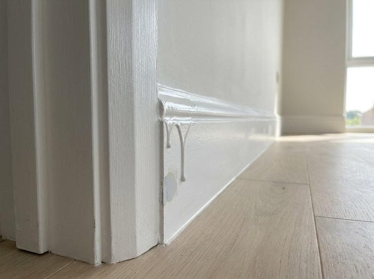 Raised paint runs and drips remain on the skirting beside the door architrave.