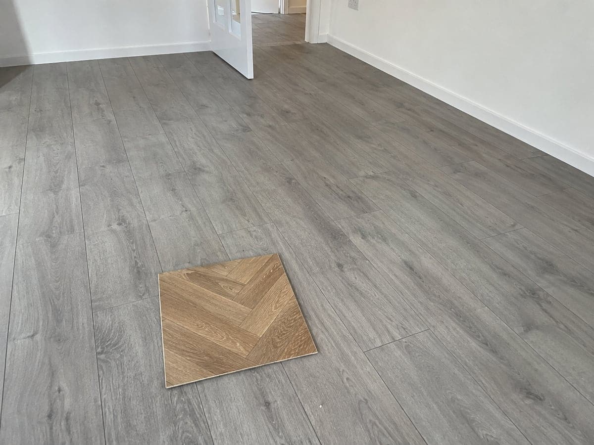 Grey straight-laid planks have been fitted. The homeowner confirmed warm oak parquet as the selected finish and showed the approved sample during the visit.